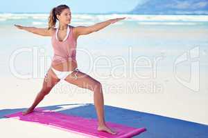 Yoga is the poetry of movement. Shot of a young woman doing yoga at the beach.