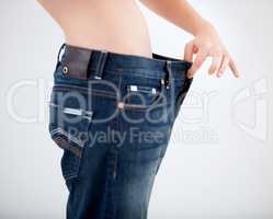 Changing her diet has worked for her. Cropped image of a woman pulling the waistband of her pants - Weight Loss.