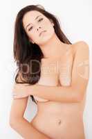 This is just a preview. Cropped portrait of an attractive young woman posing topless against a wall.