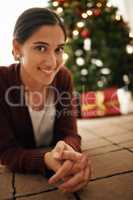 Have a holly jolly christmas. Portrait of an attractive young woman with a Christmas tree behind her.