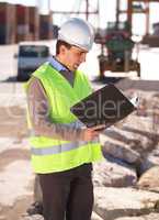 Successful engineer. Shot of a handsome young construction worker reading through the building plans.