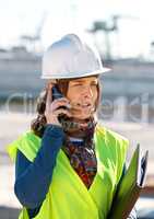 Sorting out the construction needs. A female construction worker talking on the phone.