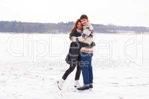 Winter romance. A young couple on an ice skating date at a frozen natural lake.