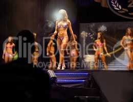 Beauty and braun. A female bodybuilding contestant walking the stage for the judges.