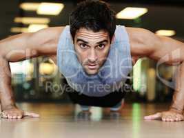 Feeling the burn. Portrait of a handsome man wearing sports clothing doing pushups at the gym.