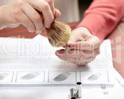 Detailed examination to catch the criminal. Cropped shot of a forensic scientist dusting a bullet above a print out of fingerprints.