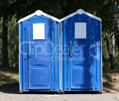 Two portable toilet cabins in park at dry sunny summer day