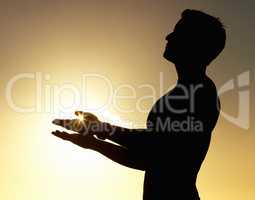Salutation to the sun. A silhouette of a man standing calmly with his hands raised.