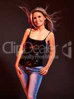Adding some sparkle to a casual look. A woman posing in a studio wearing jeans and a sparkly black top.