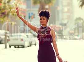 Its time to head home. Shot of a fashionable young woman waving down a cab in the city.