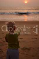 What summer is for. Rearview of a little boy on a beach at sunset pointing to the setting sun.