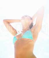 Sexy female in bikini against a bright background. Upward view of a sensuous female in bikini against the bright sky.