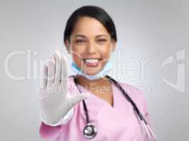 Stop covid in its tracks. Cropped portrait of an attractive young female healthcare worker gesturing stop while standing in studio against a grey background.