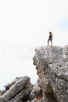 Leaving the world behind. A rock climber standing on the top of a cliff.