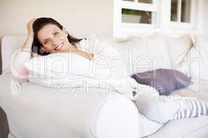 Shes just having a lazy day. An attractive woman brunette relaxing on a sofa indoors.