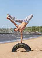 Showing off his breakdancing talent. A strong young man doing a breakdance move at the beach.