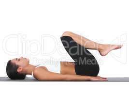 Holding her core in tightly. A young woman doing stretches while isolated on white.