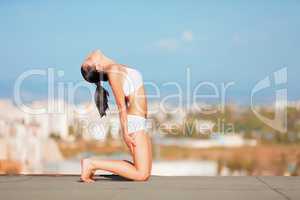 Stretching to the sky. Shot of an attractive young woman in workout gear doing yoga on a rooftop.