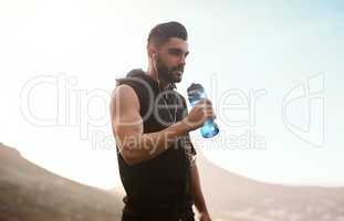 Stay hydrated to optimize your workout. Shot of a sporty young man drinking water while exercising outdoors.