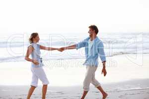 Tango on the beach. A happy couple holding hands as the sunsets on the beach.