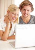 Chatting with friends via the internet. A happy young couple using a laptop to browse the net.