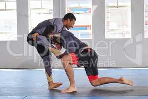 Self defence is an important part of life. Full length shot of a jiu jitsu sensei sparring with one of his students during a class.