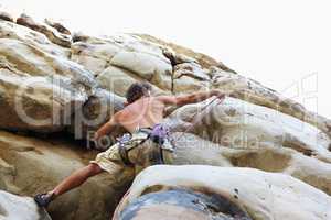 Skill is key. A rock climber climbing up a cliff face.