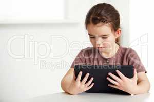 Digital age for all ages. Shot of an adorable little girl reading a digital tablet.