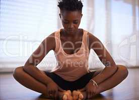 Clearing her mind and body during warm up. Shot of a young woman dancer stretching in a studio.