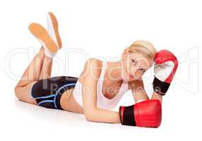 Shes a knock out. Portrait of a beautiful woman lying on the floor while wearing boxing gloves.