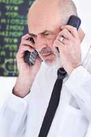 Hes a good financial middleman. Shot of a mature stock broker speaking on two mobile phones at once.