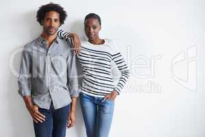 Simple and stylish. A portrait of a stylish young couple standing together affectionately against a white wall.