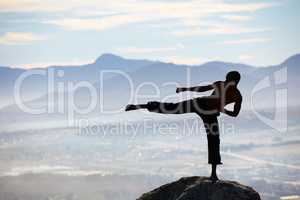 Perfect balance and technique. A male kickboxer practising his kicking technique on a mountain peak.