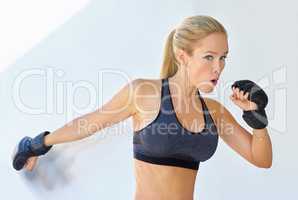 Shes a lean, mean fighting machine. Shot of a sporty young woman training with mma gloves.