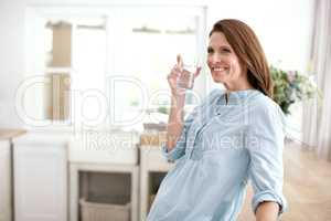 Keeping hydrated at home. A mature woman holding a glass of water and looking away.