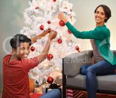 So much Christmas spirit. A portrait of two beautiful young woman decorating a Christmas tree.