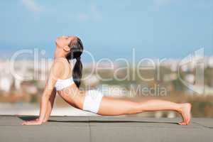 Posture perfect. Shot of an attractive young woman in workout gear doing yoga on a rooftop.