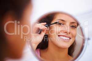 Woman applying mascara. Reflection of a beautiful woman applying mascara.