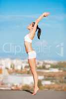 Reach for the sun. Shot of an attractive young woman in workout gear stretching on a rooftop.