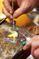 Careful concentration is key in this process. Cropped view of a manufacturing jeweler heating up solder and using a soldering pick.