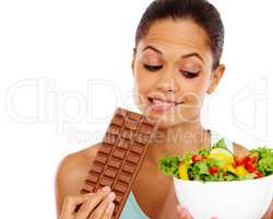 She knows the correct choice. A beautiful young woman choosing between a healthy salad an a chocolate slab.