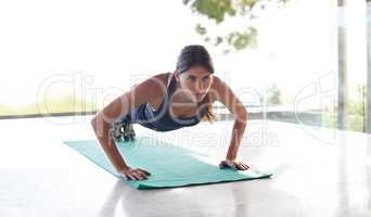 Working on her upper body. Shot of an attractive young woman working out in a studio with a view.