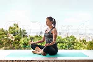 Overall wellbeing.... Full-length shot of a sporty young woman doing yoga on a balcony.