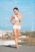 Taking in the morning rays. Shot of an attractive young woman in workout gear doing yoga on a rooftop.