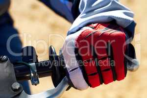 Protection for the hands is essential in motocross. Closeup of a dirt bikers hand wearing a glove.