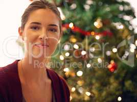 Sending seasons greetings. Portrait of a beautiful young woman in front of a christmas tree.