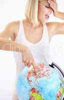Travelling is her passion. A pretty young woman covering her eyes and pointing at her next destination on a globe.