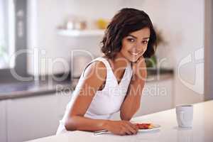 Happiness is a leisurely breakfast. Portrait of a young woman enjoying breakfast at home.