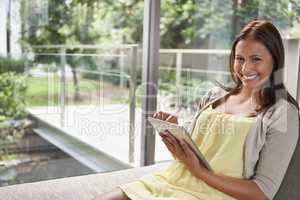 This is my quiet place. Shot of an attractive young woman using a digital tablet while relaxing indoors.