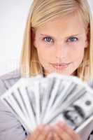 You have to work hard if you want this. A woman holding up a wad of cash with a challenging look in her eyes.